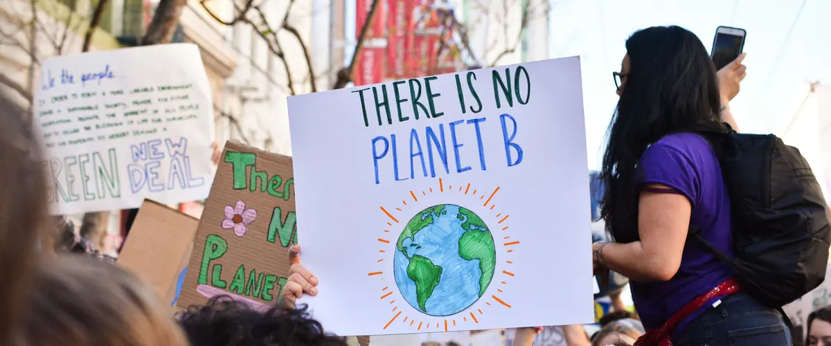 ESRS-40a contested — demonstrators with a There Is No Planet B placard, and EFRAG's own board writing against the mixed approach