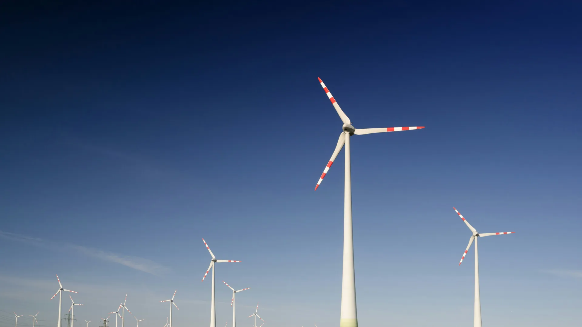ESRS 40a — turbines above a flowering field, two strata meeting at a hard line, as Article 40a's two-limb test does