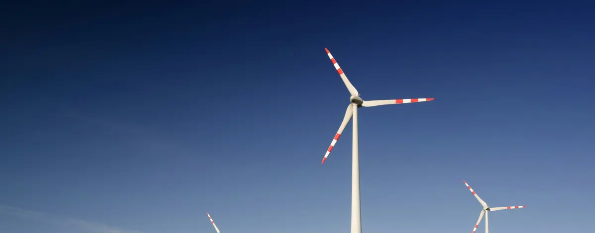 GHG emissions software and Scope 2 dual reporting — wind turbines above a flowering field, the location-based and market-based methods reported side by side