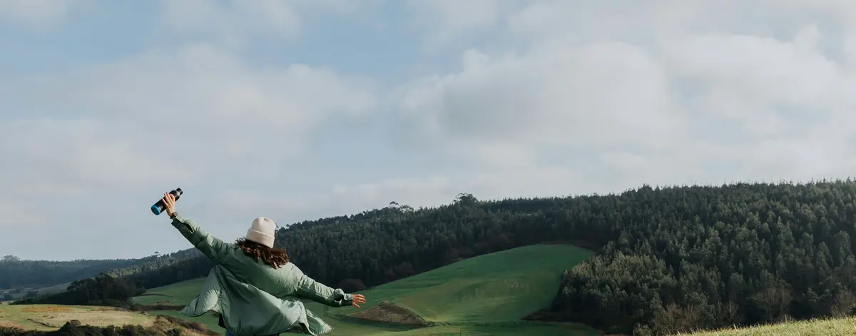 GHG reporting software in reference form — a walker standing open-armed in an open field, the sourced record